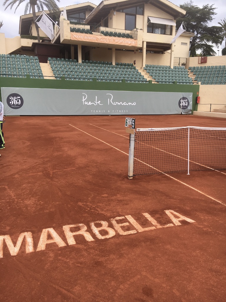 Clay court with MARBELLA painted on it at Puente Romano Tennis Club