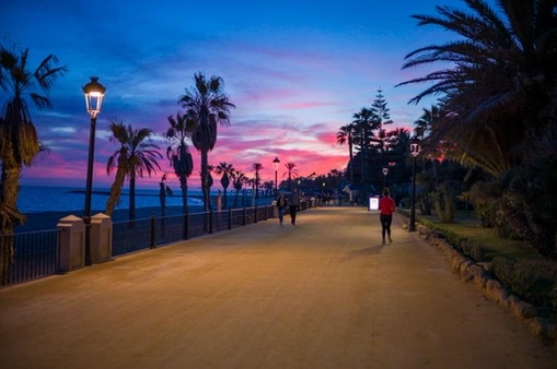 Runner on the Marbella seafront path at dusk with pink sky